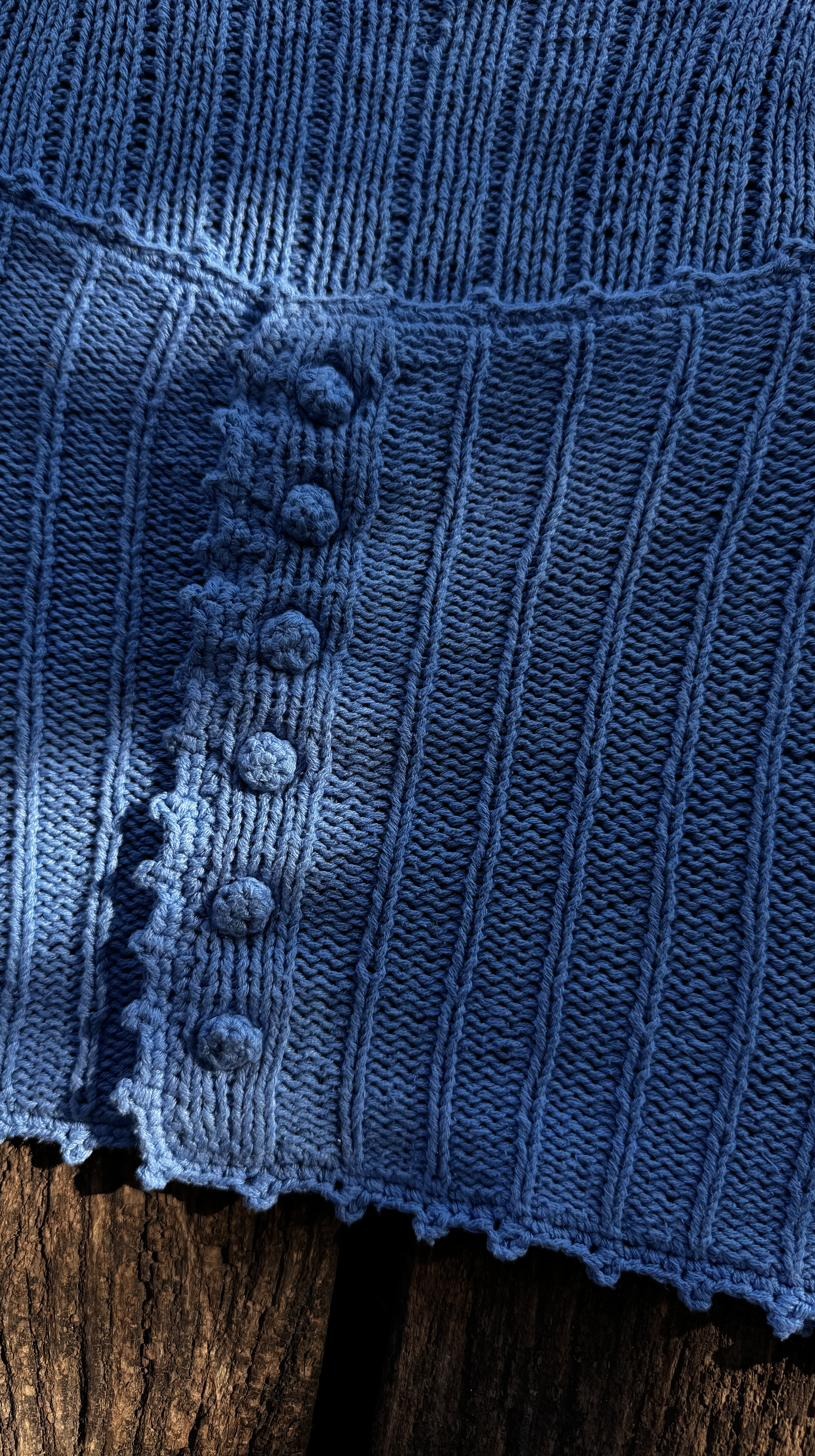 Detail of hand-knitted covered buttons on a blue ribbed cardigan